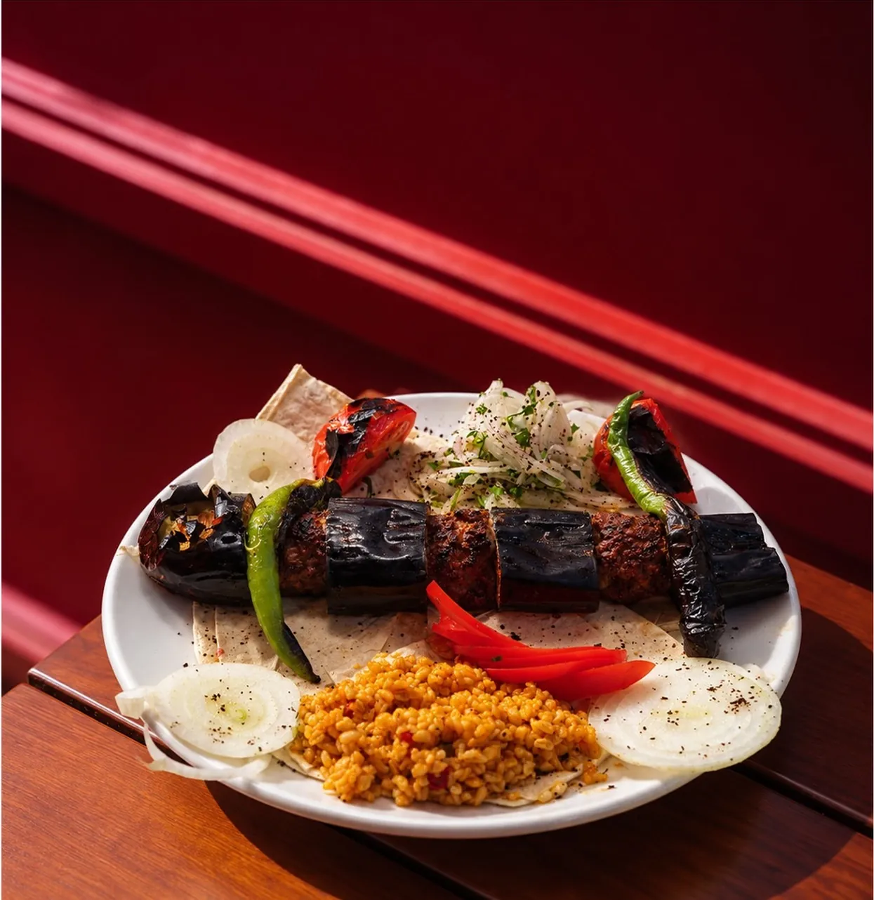 Patlıcan kebabı; bulgur pilavı, köz biber ve soğanla